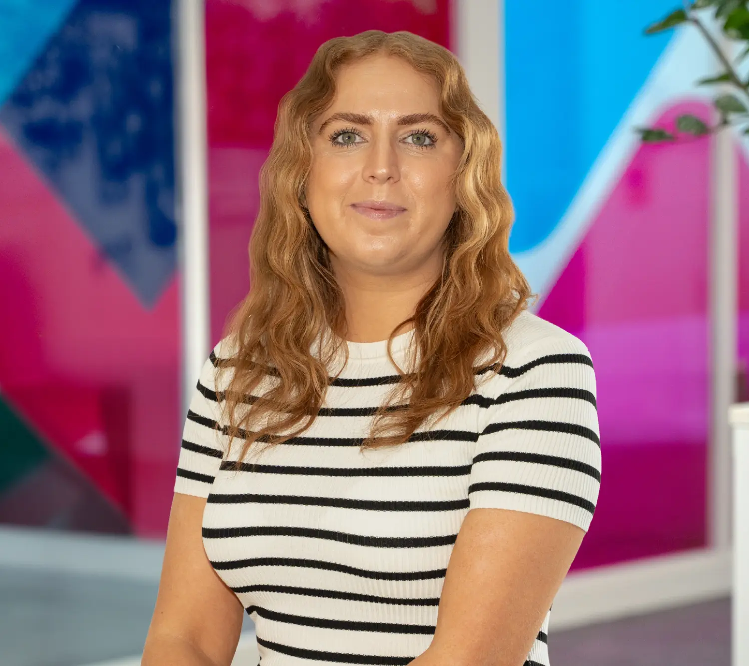 Photo of Becky Bryan, Commercial Retentions Executive at Utilita Business, sat in front of colourful glass panels.
