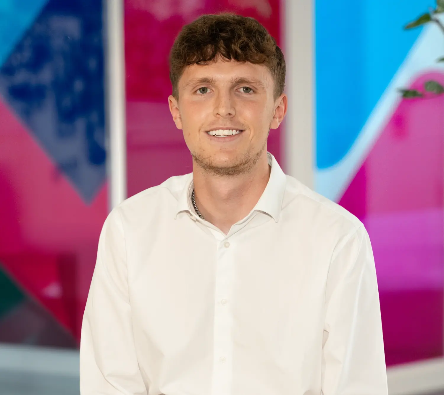 Photo of Ben McInnes, Commercial Sales Executive at Utilita Business, sat in front of colourful glass panels.