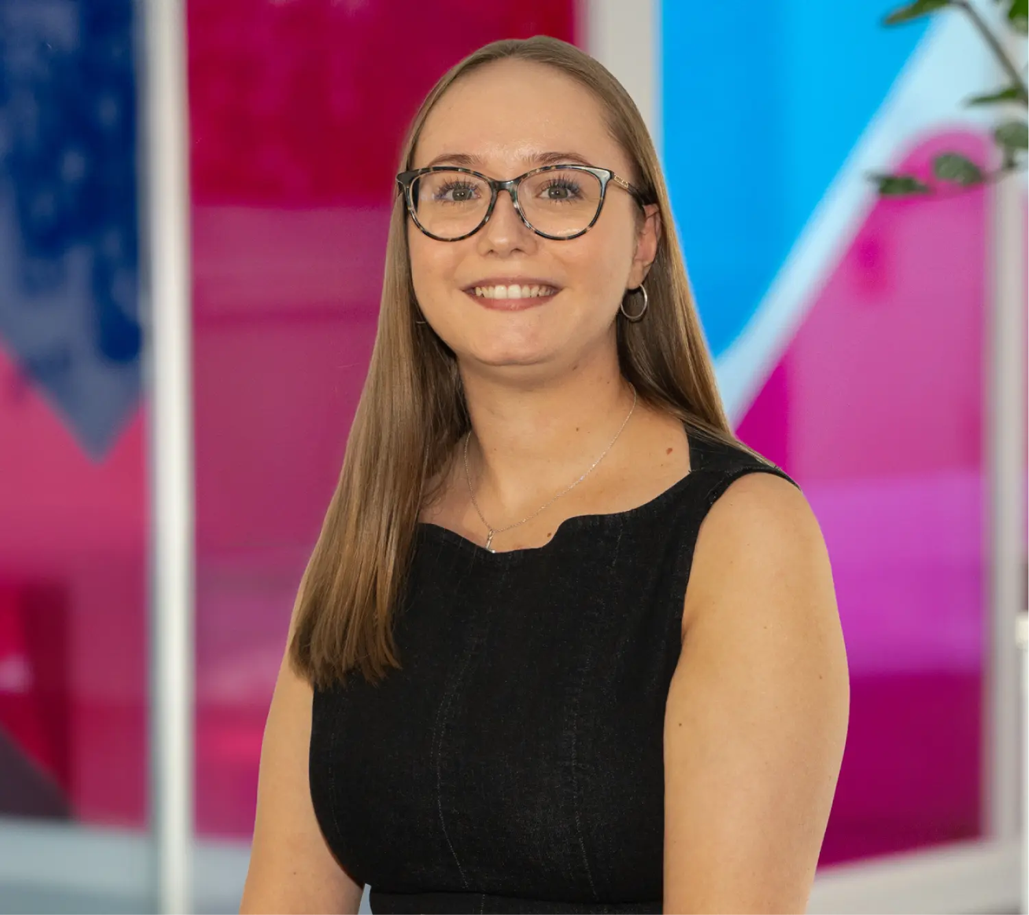 Photo of Caitlin Green, Commercial Sales Executive at Utilita Business, sat in front of colourful glass panels.
