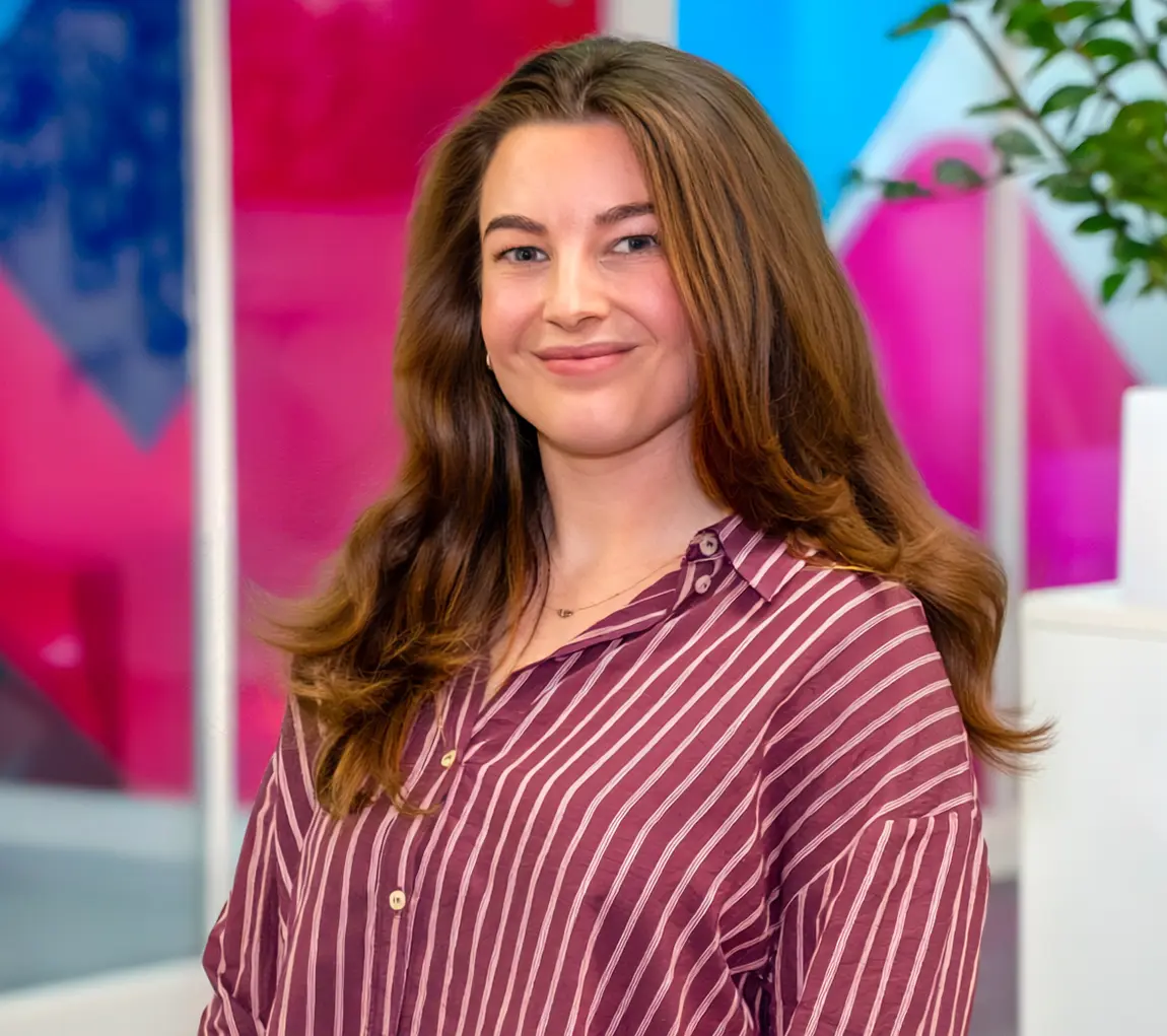 Mid-shot of Ella Moorey, Group Sustainability Lead at Utilita, sat in an office with colourful glass panels in the background.
