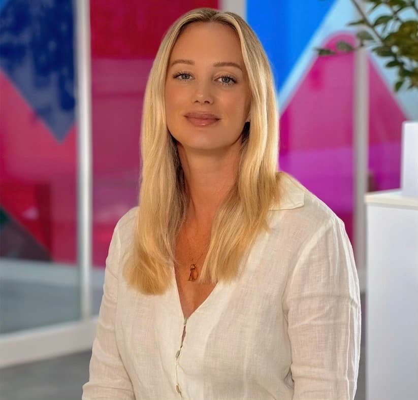 Photo of Felicity Neaves, Head of Commercial at Utilita Business, sat in front of colourful glass panels.