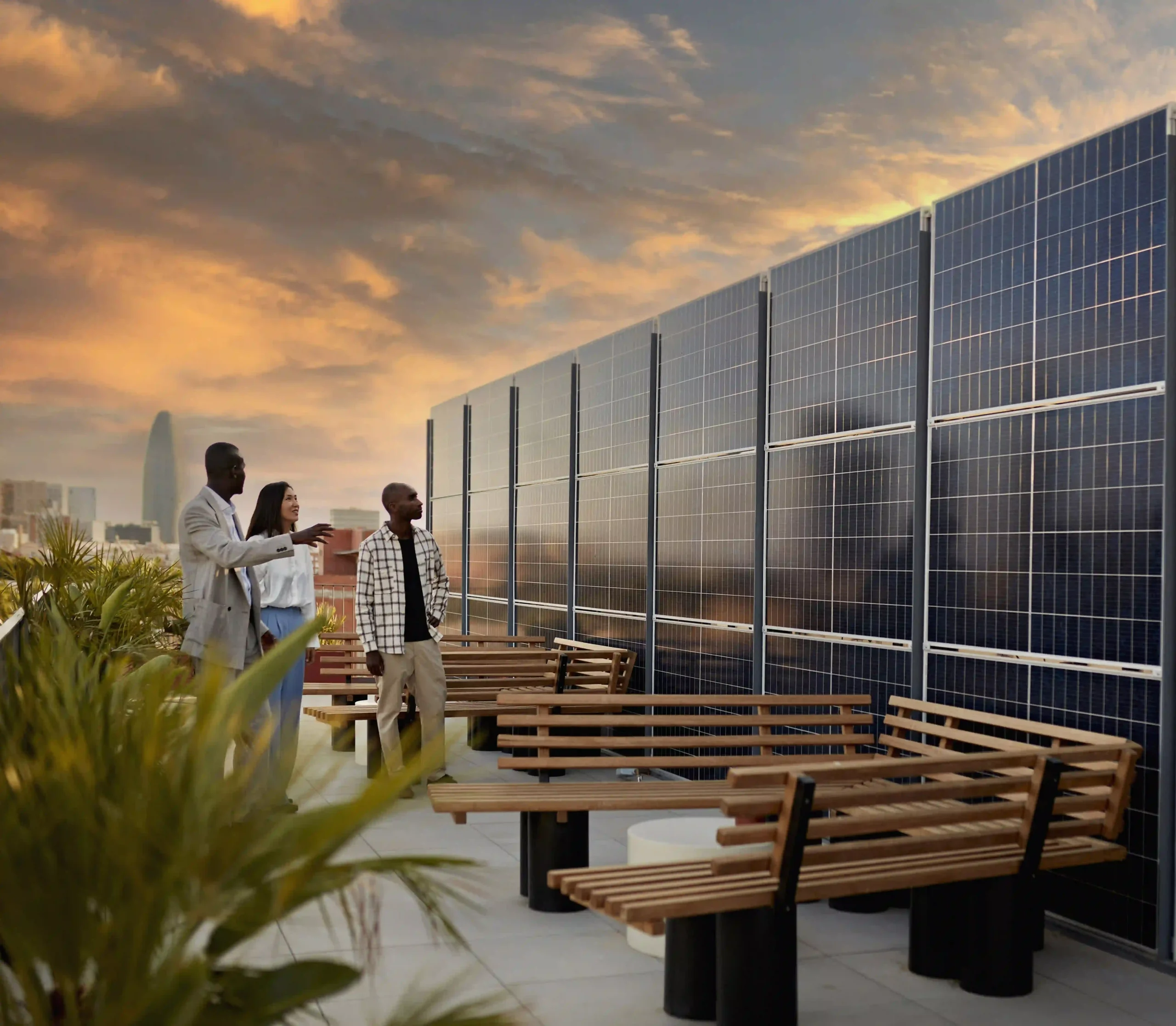Three people standing in a rooftop bar looking at a wall of commercial solar panels powering their hospitality business.