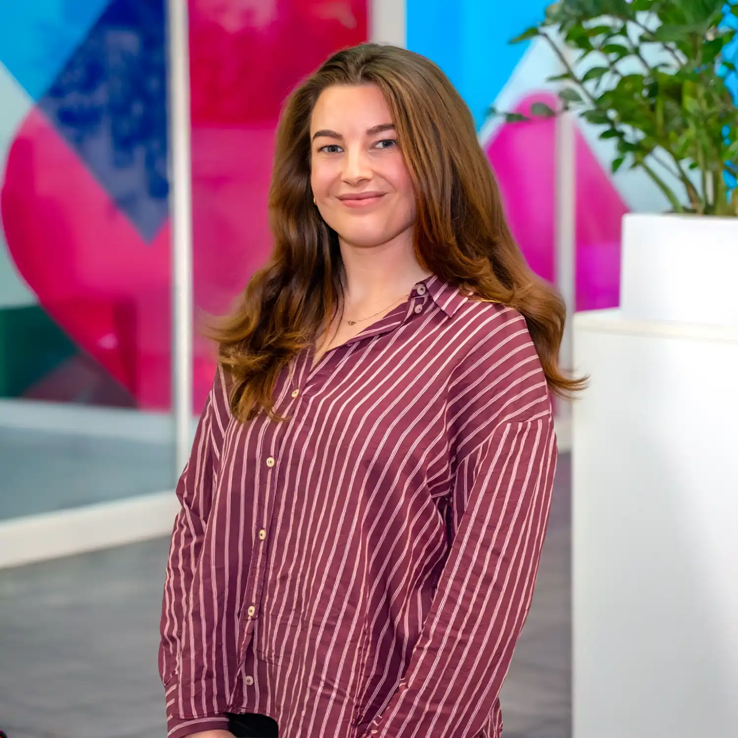 Mid-shot of Ella Moorey, Group Sustainability Lead at Utilita, sat in an office with colourful glass panels in the background.